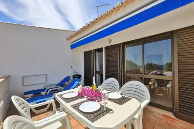 a white dining table and chairs on a patio at Beach Front A in Luz