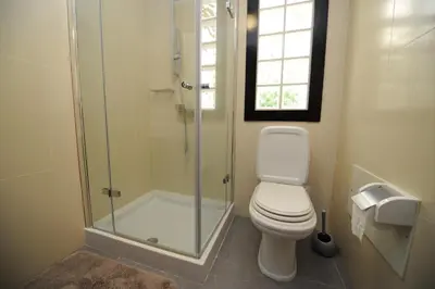 a bathroom with a toilet and a glass shower at BHF Residences Bordadeira in Arco da Calheta