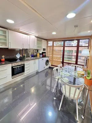 a kitchen with a glass table and white cabinets at Arriaga Marina Club Apartament in Funchal