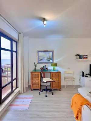 a bedroom with a desk and a bed and a window at Arriaga Marina Club Apartament in Funchal