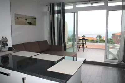 a kitchen and living room with a couch and a balcony at Ventur Flat in Caniço