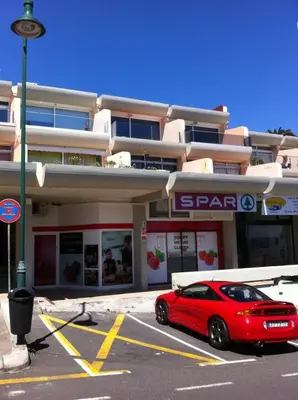 a red car parked in a parking lot in front of a building at Ventur Flat in Caniço