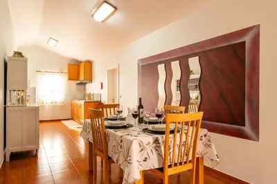 a dining room with a table and chairs and a kitchen at Apartamento Celia in Arco da Calheta