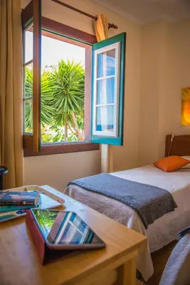 a room with two beds and a table and a window at Villa Ricardo in Porto da Cruz