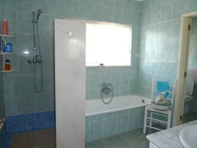 a bathroom with a tub and a shower with a window at Highview Villa in Lagos