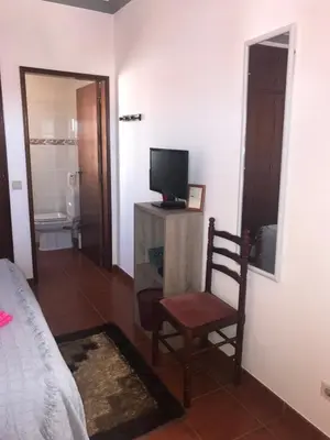 a bedroom with a tv and a chair in a room at Casa Da Estela in Carrapateira
