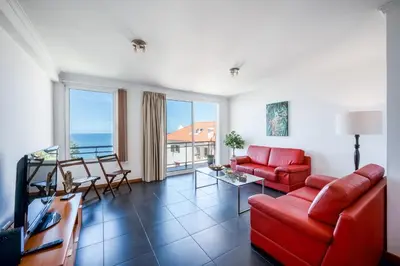 a living room with red furniture and a view of the ocean at Villa São Tiago by Amazing Madeira in Funchal