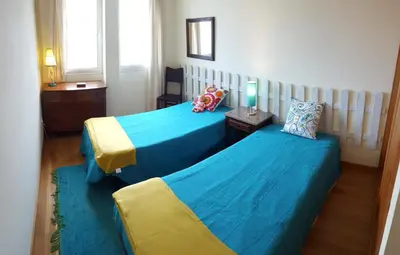 two beds in a room with blue and yellow at Sotavento Guest House in Porto Santo