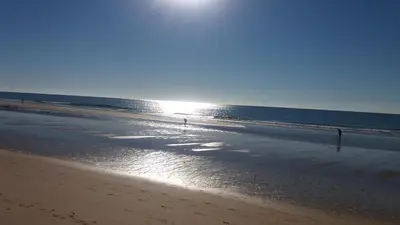 a beach with the sun reflecting on the water at Casa Da Paz in Salema