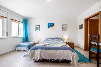 a bedroom with a bed and two windows at Casa Da Paz in Salema