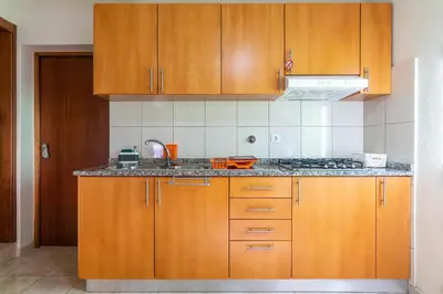 a kitchen with wooden cabinets and a sink at Apartamento Teixeira in Arco da Calheta