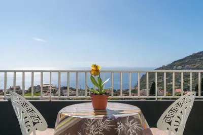 a table with a flower on top of a balcony at Apartamento Teixeira in Arco da Calheta