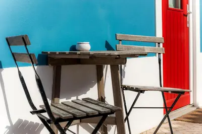 a wooden table and a chair next to a wall at Cercas Velhas in Sagres