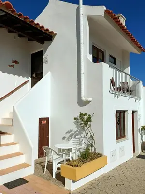 a white house with a table and chairs at Casa dos Pinheiros in Praia da Arrifana