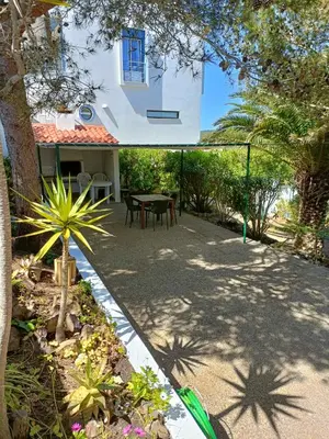 a patio of a house with a table and chairs at Casa dos Pinheiros in Praia da Arrifana