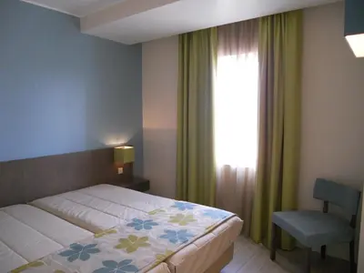 a bedroom with a bed and a chair and a window at INATEL Porto Santo in Porto Santo
