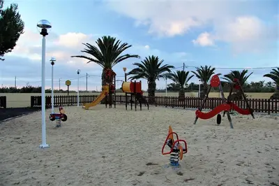 a playground in the sand with play equipment and palm trees at INATEL Porto Santo in Porto Santo