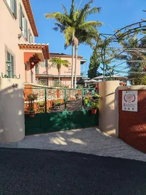 a green gate in front of a house with a palm tree at A Casa Do Caseiro in Funchal