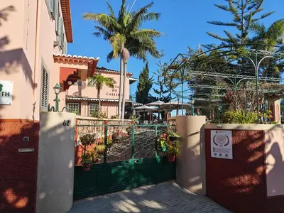 a green gate in front of a building with palm trees at A Casa Do Caseiro in Funchal