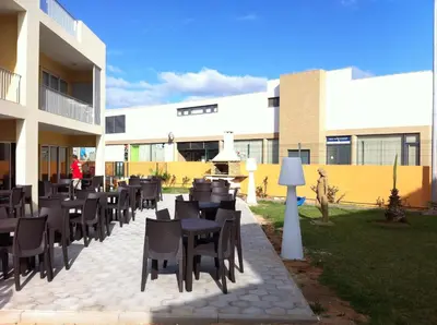 a patio with tables and chairs in front of a building at Paraiso Dourado in Porto Santo