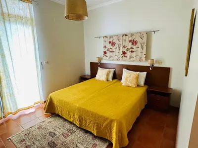 a bedroom with a bed with a yellow bedspread at Villa Babel in Garajau