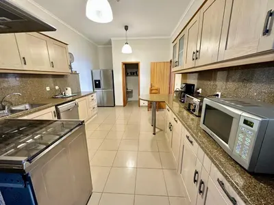 a large kitchen with white cabinets and stainless steel appliances at Villa Babel in Garajau