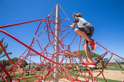a woman is climbing on a playground at NAU Salema Beach Village in Salema