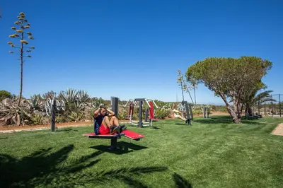 two people sitting on a bench in a park at NAU Salema Beach Village in Salema