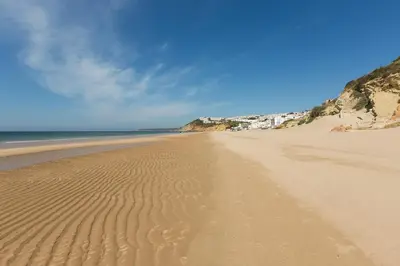 a sandy beach with ripples in the sand at NAU Salema Beach Village in Salema