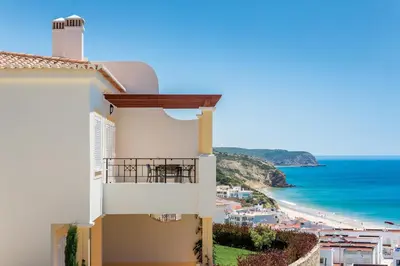 a white building with a balcony overlooking the beach at NAU Salema Beach Village in Salema