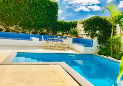 a swimming pool with a table and chairs next to a house at Casa da Rochinha com piscina privada in Funchal