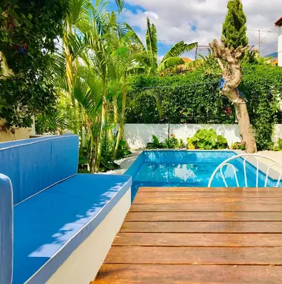 a pool with a blue bench next to a wooden deck at Casa da Rochinha com piscina privada in Funchal