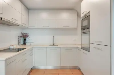 a white kitchen with white cabinets and a sink at Casa da Rochinha com piscina privada in Funchal