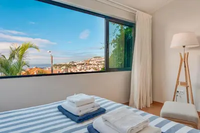 a bedroom with a bed with a large window at Casa da Rochinha com piscina privada in Funchal