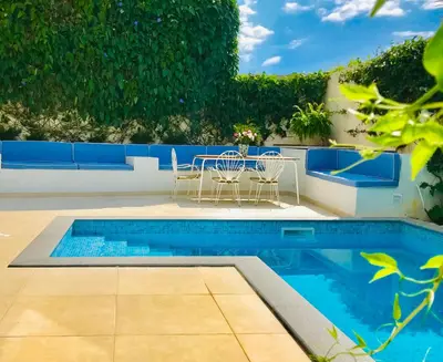 a swimming pool with chairs and a table next to it at Casa da Rochinha com piscina privada in Funchal