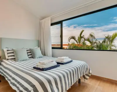a bedroom with a large window with a view of the ocean at Casa da Rochinha com piscina privada in Funchal