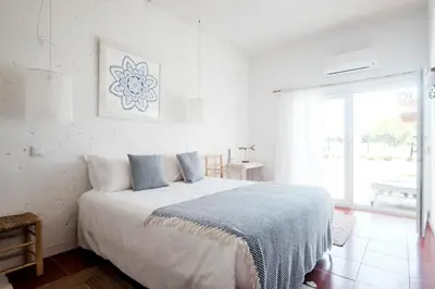 a white bedroom with a large bed and a window at Utopia in Aljezur