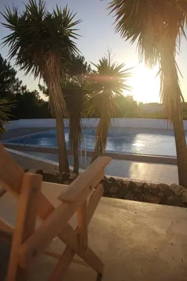 a wooden chair sitting next to a pool with palm trees at Utopia in Aljezur