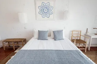 a white bed with blue pillows in a room at Utopia in Aljezur