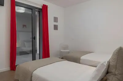two beds in a room with red curtains at Casa da Maresia by An Island Apart in Porto Santo