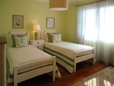 two beds in a green bedroom with a window at The best sea view in Madeira - Casa Farol in Fajã da Ovelha