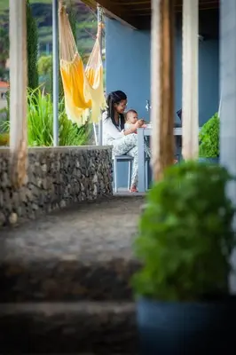 a woman holding a baby while sitting at a table at Casas Da Vereda in Estreito da Calheta