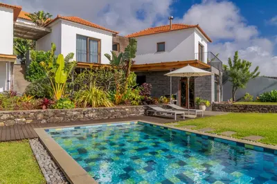a villa with a swimming pool in front of a house at Casas Da Vereda in Estreito da Calheta