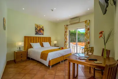a bedroom with a bed and a desk and a window at Canavial I & II Apartamentos in Lagos