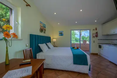 a bedroom with a bed and a table and a kitchen at Canavial I & II Apartamentos in Lagos