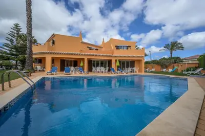 a villa with a swimming pool in front of a house at Canavial I & II Apartamentos in Lagos