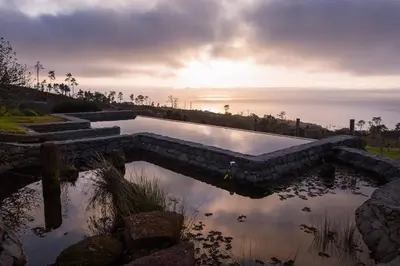 a pool of water with the sunset in the background at Casas da Levada in Ponta do Pargo