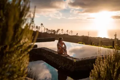a woman sitting on the edge of a swimming pool at Casas da Levada in Ponta do Pargo