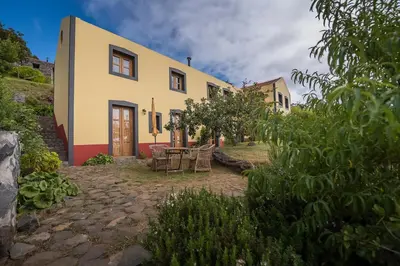 a house with a table and chairs in front of it at Casas da Levada in Ponta do Pargo