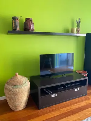 a flat screen tv on a stand with a green wall at Casa do Cavacas in Funchal